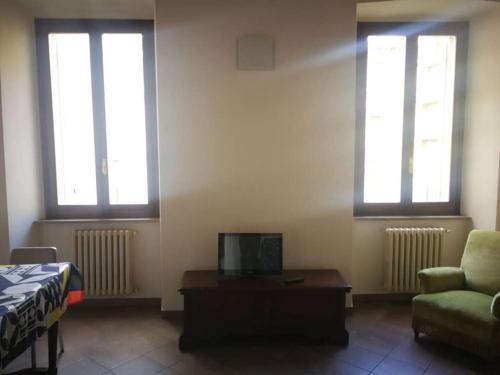 Cette chambre dispose de deux fenêtres, d'un canapé et d'une table. dans l'établissement St Francis Apartaments, à Foligno