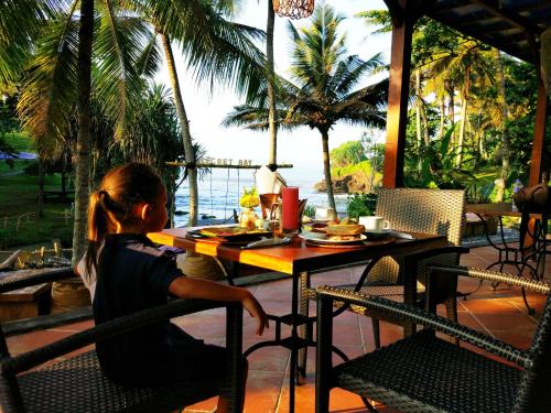 منتجع غاجاه مينا بيتش في Selemadeg: فتاة صغيرة تجلس على طاولة وعليها طعام