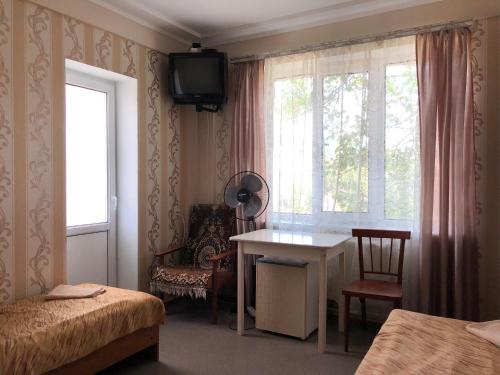 アナパにあるGuest House on Sovetskaya 73のベッド、デスク、窓が備わる客室です。