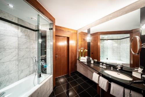 a bathroom with a sink, mirror, and bathtub at Seaside Park Hotel Leipzig in Leipzig