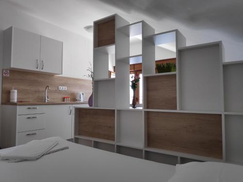 a kitchen with white cabinets and wooden shelves at Apartman Anicic in Podaca