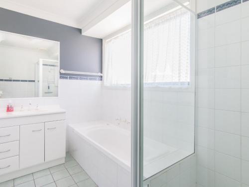 a white bathroom with a tub and a shower at 1 54 Parkes Street in Tuncurry