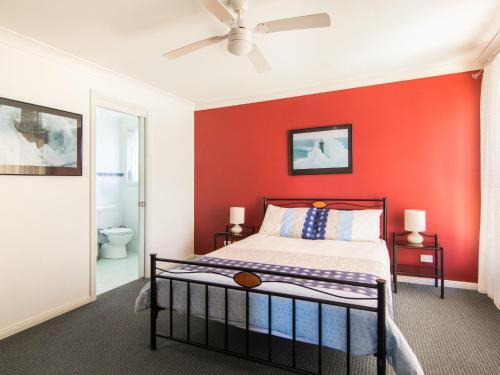 Un dormitorio con una pared roja y una cama en 1 54 Parkes Street en Tuncurry