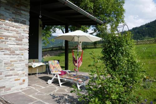 a chair and an umbrella on a patio at Wohlfühlchalet Tirol in Reith im Alpbachtal