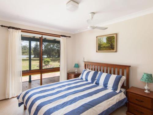 a bedroom with a bed and a large window at 11 Bay Street - waterfront holiday in Tuncurry