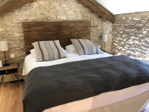 een slaapkamer met een groot bed en een stenen muur bij FOUR DE CONY in Saumane-de-Vaucluse