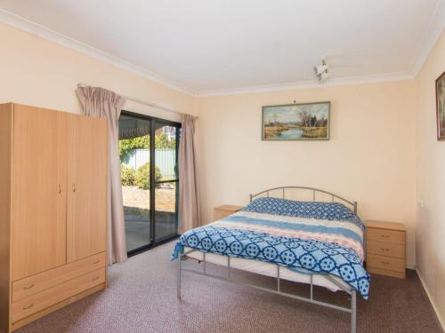 a bedroom with a bed and a dresser and a window at 11 Peel Street in Tuncurry