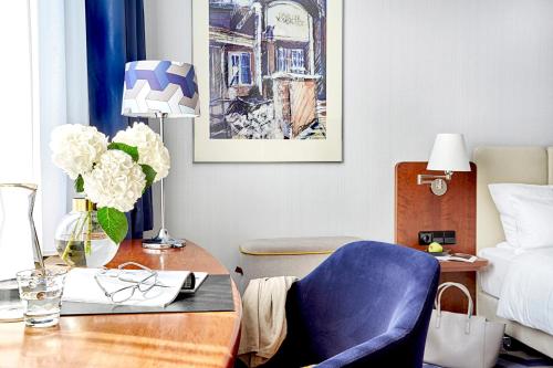 Schlafzimmer mit einem Schreibtisch, einem blauen Stuhl und einem Bett in der Unterkunft Seaside Park Hotel Leipzig in Leipzig