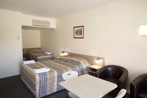 a hotel room with two beds and a table and chairs at Pioneer Motel Goondiwindi in Goondiwindi