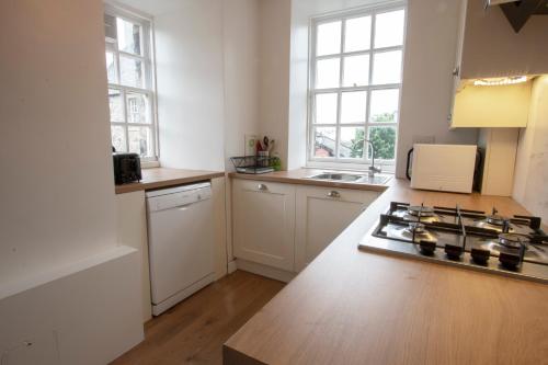 a kitchen with white cabinets and a stove top oven at Cadell House Apt - Royal Mile in Edinburgh
