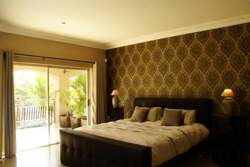 African Palm Cottage and Guesthouse في دوربانفيل: غرفة نوم بسرير كبير وبلكونة