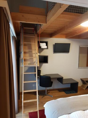 a loft bed in a room with a desk and a ladder at Hotel Roggerli in Hergiswil