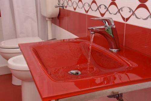 a red sink in a bathroom with a toilet at Villa Letizia in Campofelice di Roccella