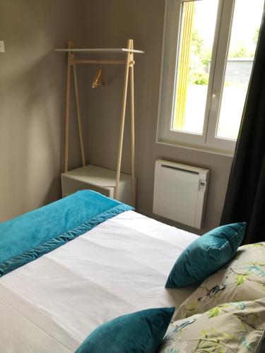 a bedroom with a bed with blue pillows and a window at La petite maison des gîtes de Joséphine in Saint-Dyé-sur-Loire