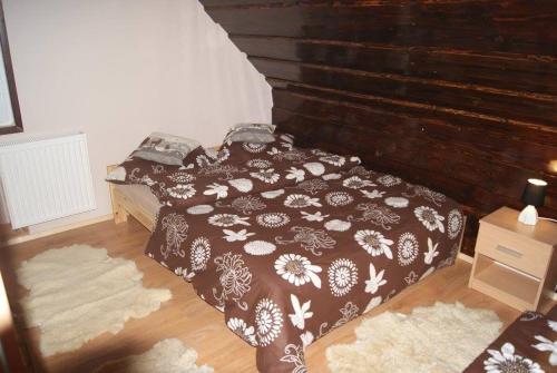 1 dormitorio con 1 cama y pared de madera en Domek Całoroczny OSTOJA en Istebna