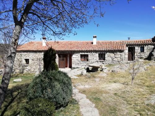 una antigua casa de piedra con techo rojo en Casa Rural La Pontezuela Abajo, en Navarredonda de Gredos