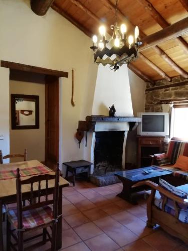 sala de estar con chimenea y mesa en Casa Rural La Pontezuela Arriba, en Navarredonda de Gredos