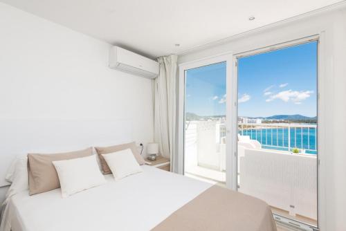 um quarto com uma cama branca e uma grande janela em Luisamar Sea View em Manacor