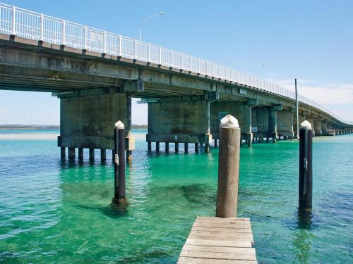 a bridge over a body of water with poles in the water at Champagne Court 1 in Tuncurry