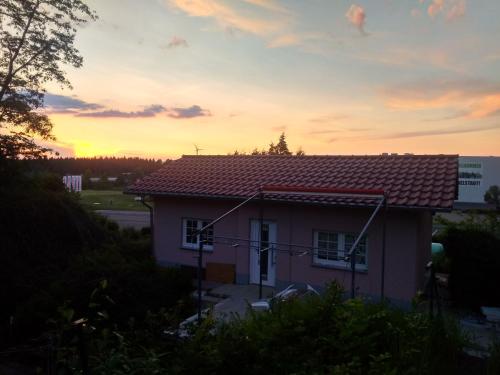 a house with a sunset in the background at Kleines Gartenhaus am Mahler in Großschirma