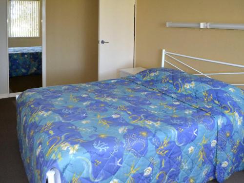 a bedroom with a bed with a blue comforter at Fairholme 5 in Tuncurry