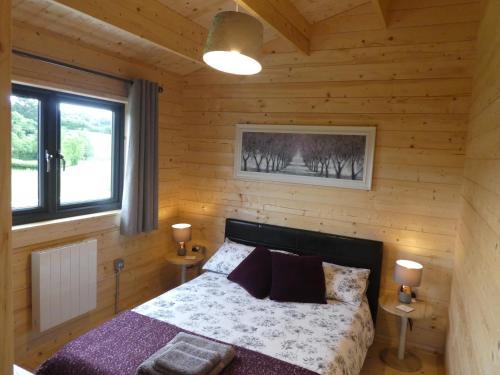 a bedroom with a bed in a wooden cabin at Pound Farm Holidays - Orchard Lodge in Cullompton