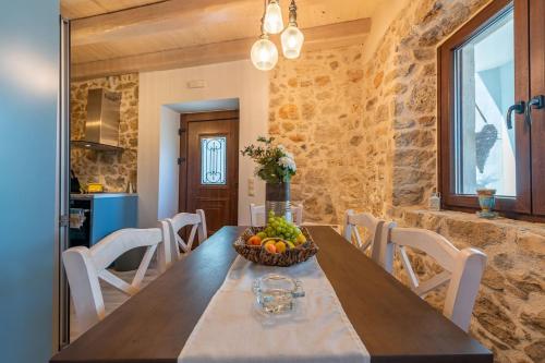 a dining room with a table with a bowl of fruit at Amelia & Nicholas Stone Houses in Doukádes