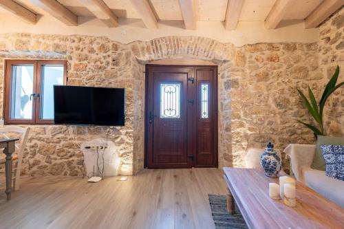 a living room with a tv and a stone wall at Amelia & Nicholas Stone Houses in Doukádes