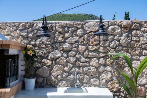 a stone wall with a sink and two lights at Amelia & Nicholas Stone Houses in Doukádes