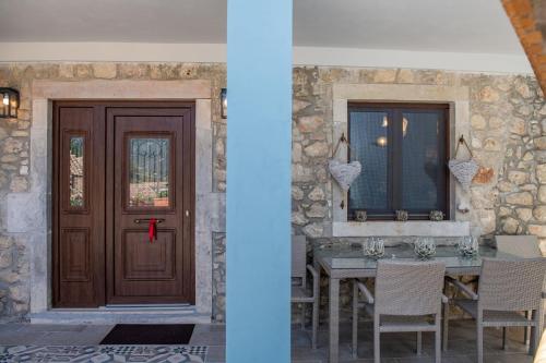 two pictures of a door and a table with chairs at Amelia & Nicholas Stone Houses in Doukádes