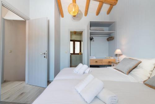 two white beds in a room with a mirror at Amelia & Nicholas Stone Houses in Doukádes