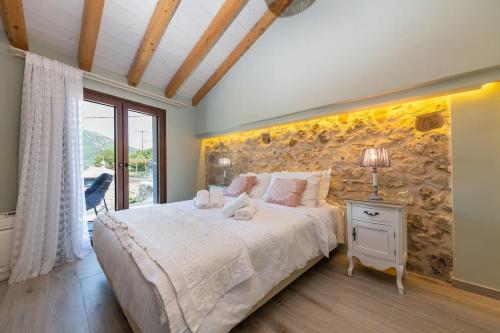 a bedroom with a large bed and a stone wall at Amelia & Nicholas Stone Houses in Doukádes