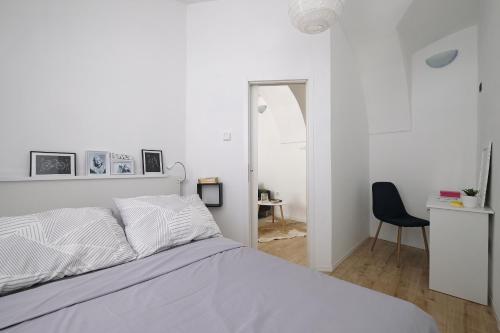 a white bedroom with a bed and a chair at Stone gate in Zagreb