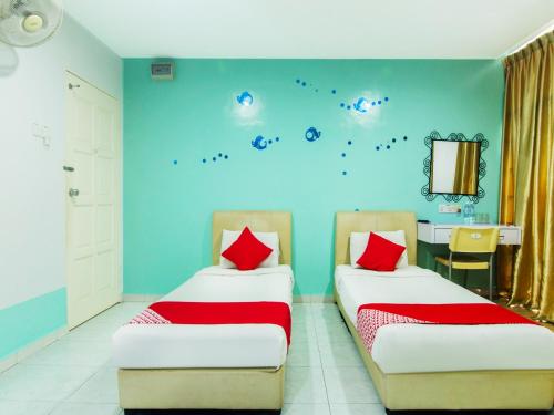 2 camas en una habitación con paredes azules y almohadas rojas en OYO 880 Hotel Purple Town, en Sekinchan