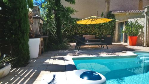 a pool with a table and a yellow umbrella at Le patio d'olivier in Lalinde