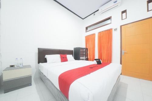 a bedroom with a large white bed with a red blanket at RedDoorz Syariah near Mall Roxy Banyuwangi 2 in Banyuwangi