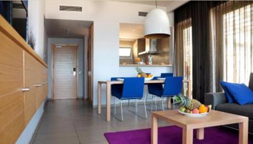 a living room with a table and blue chairs at Mercure Quemado Al-Hoceima Resort in Al Hoceïma