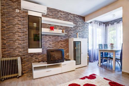 ein Wohnzimmer mit einem TV und einer Ziegelwand in der Unterkunft Stojkovic Family Apartments in Tivat