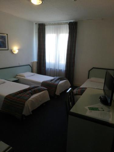 une chambre d'hôtel avec deux lits et un bureau dans l'établissement Hôtel de Nevers, à Lourdes