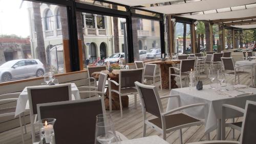 a restaurant with white tables and chairs and windows at Piccolo Hotel in Moneglia