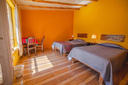 two beds in a room with yellow walls and wooden floors at Le Foyer Colca in Yanque