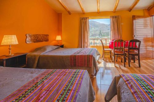 a hotel room with two beds and a table and chairs at Le Foyer Colca in Yanque