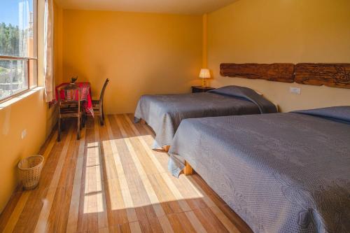 a bedroom with two beds and a table and a window at Le Foyer Colca in Yanque