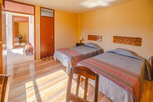 two beds in a room with yellow walls at Le Foyer Colca in Yanque