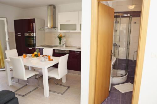 a kitchen and a dining room with a white table and chairs at Apartments St.Anthony in Korčula