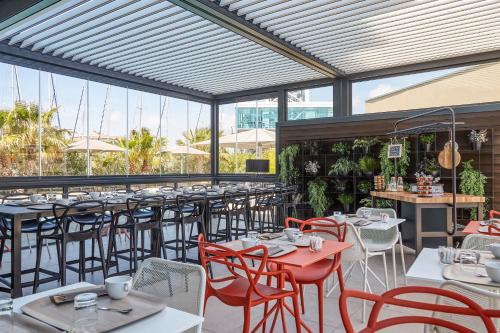 a restaurant with tables and chairs and windows at Hôtel Mercure Toulon La Seyne-Sur-Mer in La Seyne-sur-Mer