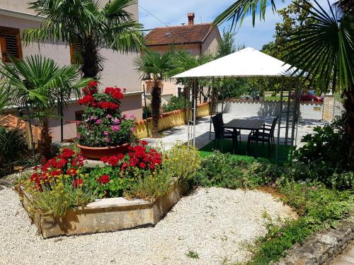 a garden with flowers and a table and an umbrella at Apartments Lori in Poreč