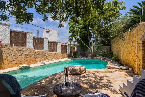 a swimming pool in a yard with a stone wall at Bright villa with salt water pool in El Campello