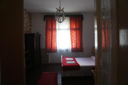 a bedroom with a red curtain and a bed with a window at Somborski salas - strogi centar in Sombor