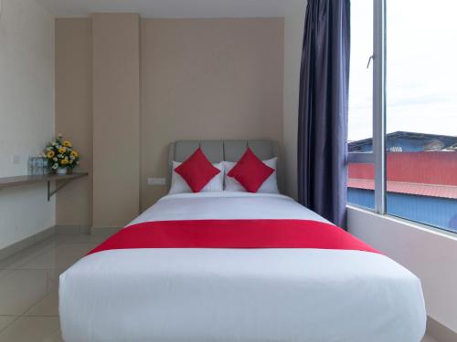 a bed with red pillows in a room with a window at Hotel Agro in Raub
